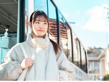 スクールバスの前に立つ学生